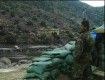 A soldier from Afghanistan's Army stares across the river border into Pakistan.  His combat base, Firebase California, sees regular attacks from Taliban forces in Pakistan.