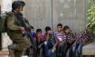 Two Israeli soldiers guard Palestinian children in Hebron